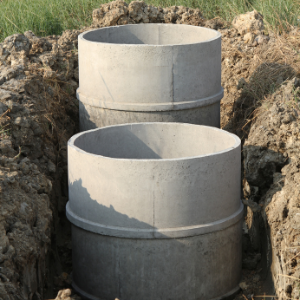 White Septic Tanks in the ground, Sun setting on them with grass surrounding the septic tanks in the ground